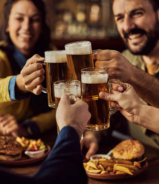 groupe d'amis faisant un toast des bières à la main dans un restaurant