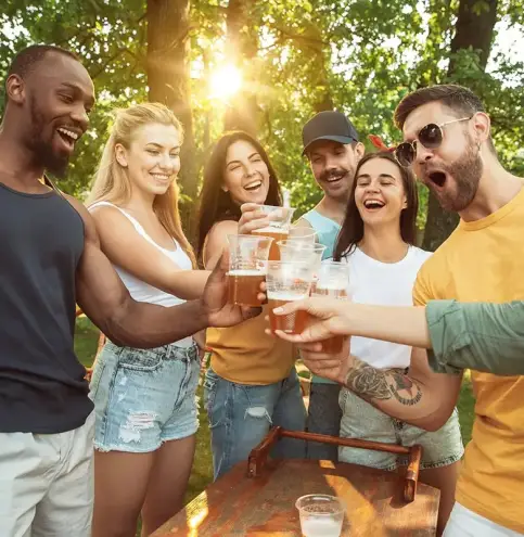 amis portant un toast avec des bière en extérieur